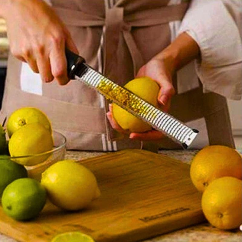 Personne utilisant un zesteur pour récupérer des zestes d'orange.
