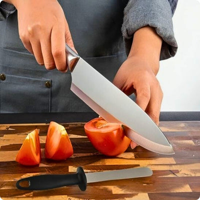 Affuteur de couteaux posé à côté d'une personne qui coupe une tomate à l'aide d'un couteau.