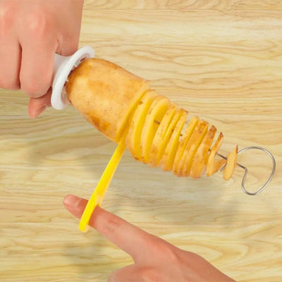 Mains qui coupent une pomme de terre en forme de spirale à l'aide d'un coupe frites manuel