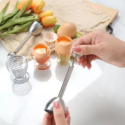 Coupe oeuf à la coque tenu par une femme dans a main en cuisine