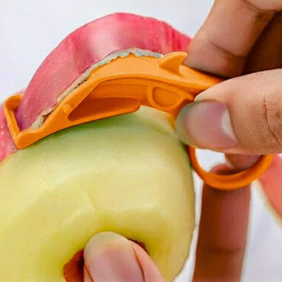 Personne en train d'éplucher une pomme avec un économe de couleur orange, elle tient la pomme de sa main gauche et l'économe de sa main droite, des épluchures sont visibles à la sortie de l'appareil.