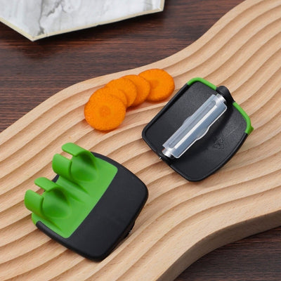 Deux économes posés sur une planche designée, on voit les deux face du produit, face de fixation sur la main et la face avec la lame, à côté des lamelles de carottes coupées.