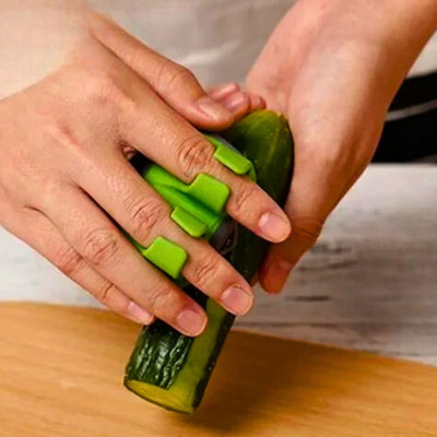 Personne en train d'éplucher un concombre avec un éplucheur qu'il tient dans sa main en mettant deux doigts dans un espace prévu à cet effet, le concombre est tenu par la main gauche au-dessus d'une planche à découper.