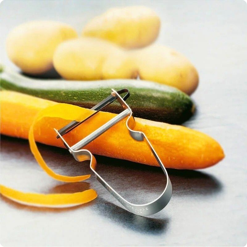 Éplucheur à légumes sur carotte avec épluchure dans lame.