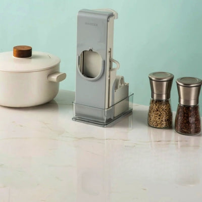 Mandoline cuisine rangée dans son bac avec ses ustensiles à côté d'une salière et une marmite posées sur un plan de travail