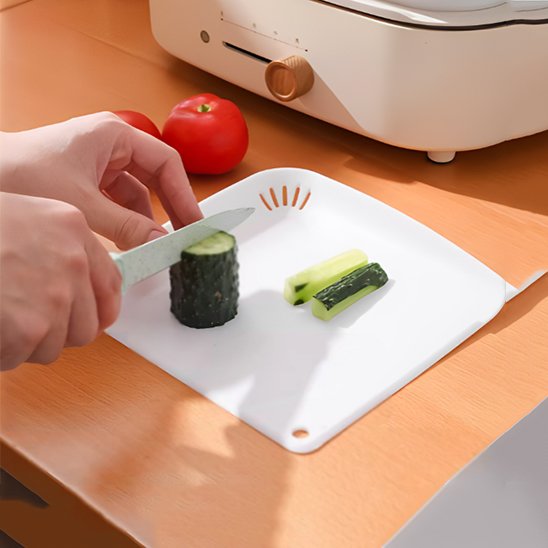 Personne qui découpe un concombre sur la planche à découper