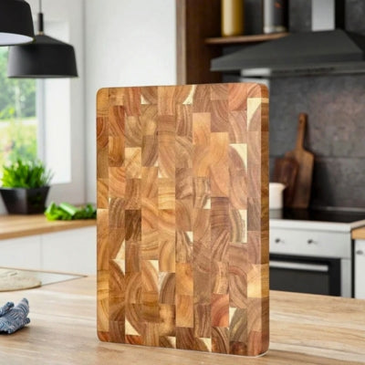 Planche à découper bois posée debout sur sa petite tranche sur un plan de travail dans une cuisine.