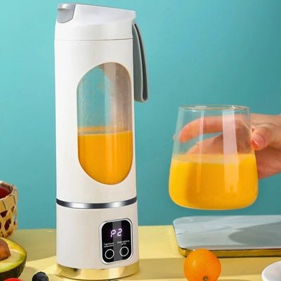 Blender mini sur table avec une personne tient verre de jus d'orange à côté.