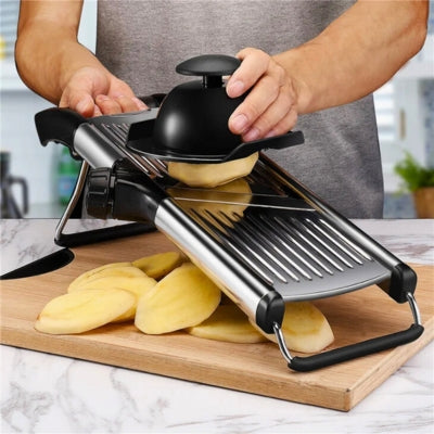 Mandoline japonaise posée sur une planche à découper et utilisée par une personne pour couper une pomme de terre en tranche. Les tranches tombent dans une assiette positionnée dessous.