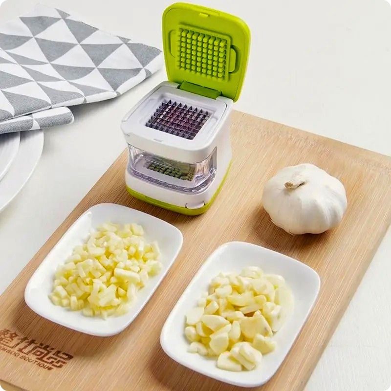 coupe ail clic ail'ine posé sur un plateau à côté assiette et ail