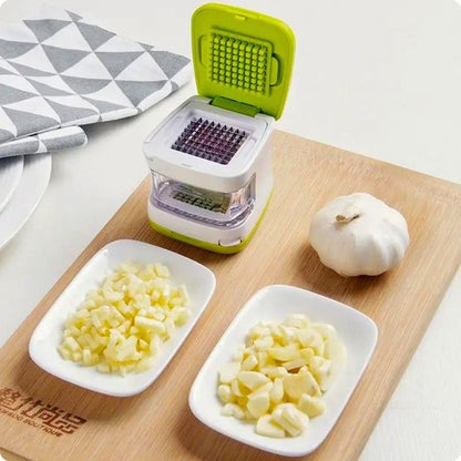 coupe ail clic ail'ine posé sur un plateau à côté assiette et ail