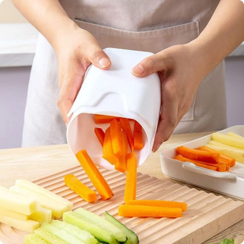 Personne qui renverse un coupe frites et fait tomber des frites de carottes