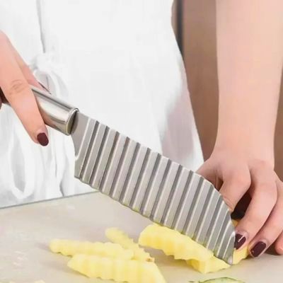 Personne utilisant un coupe frite manuel pour couper des frites ondulées