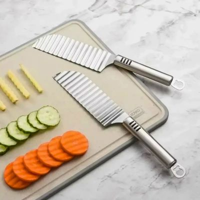 Coupe frite manuel posé sur une planche à découper avec des légumes coupés