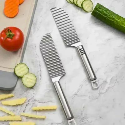 Coupe frite manuel posé sur un table avec légumes coupés à côté.