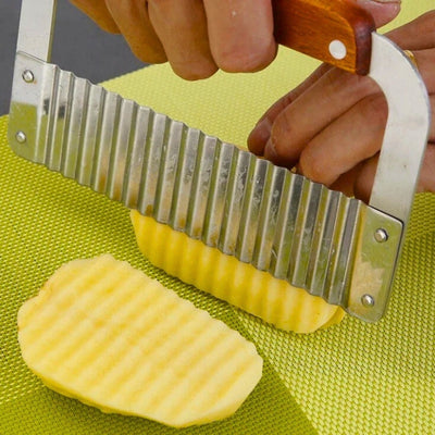 Main qui coupe une pomme de terre avec un coupe frite manuel