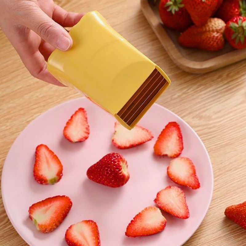 Coupe légumes manuel natur'ine tenu au dessus d'une assiette de fraise