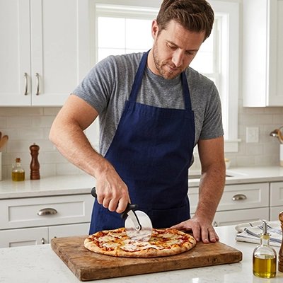 Couteau à pizza pizzet'ine utilisé par un homme en cuisine qui coupe un pizza
