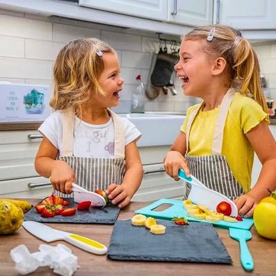 Deux enfants rigolant en coupant des légumes aveccouteau cuisine enfant