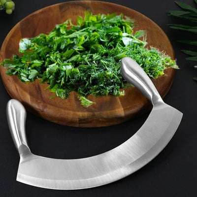 Couteau hachoir posé à cheval sur une table noire et une assiette en bois dans laquelle se trouve de la salade