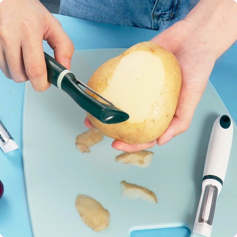 Personne en train d'éplucher une pomme de terre avec un économe cuisine.