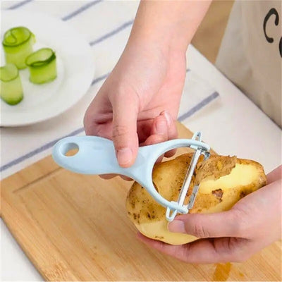 Personne qui épluche une pomme de terre avec un économe bleu au-dessus d'une planche à découper en bois. En fond, une assiette avec 3 rondelles de concombre enroulées sur elle-même posées à la verticale.