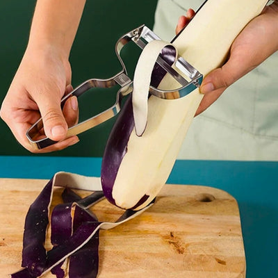 Personne en train d'éplucher une aubergine au-dessus d'une planche à découper en bois, des épluchures passent dans l'économe et des épluchures sont sur la planche.