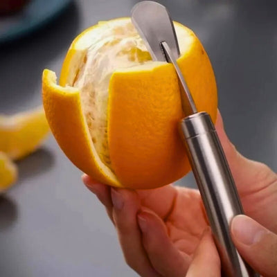 Personne en train d'éplucher une orange avec un éplucheur adapté, en utilisant la lame arrière de l'éplucheur, en arrière des quartiers d'orange
