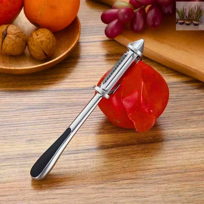 Éplucheur posé à cheval sur une tomate et une table, une part d'épluchure passe dans l'éplucheur, à côté une planche à découper et une assiette en bois avec des noix dedans.