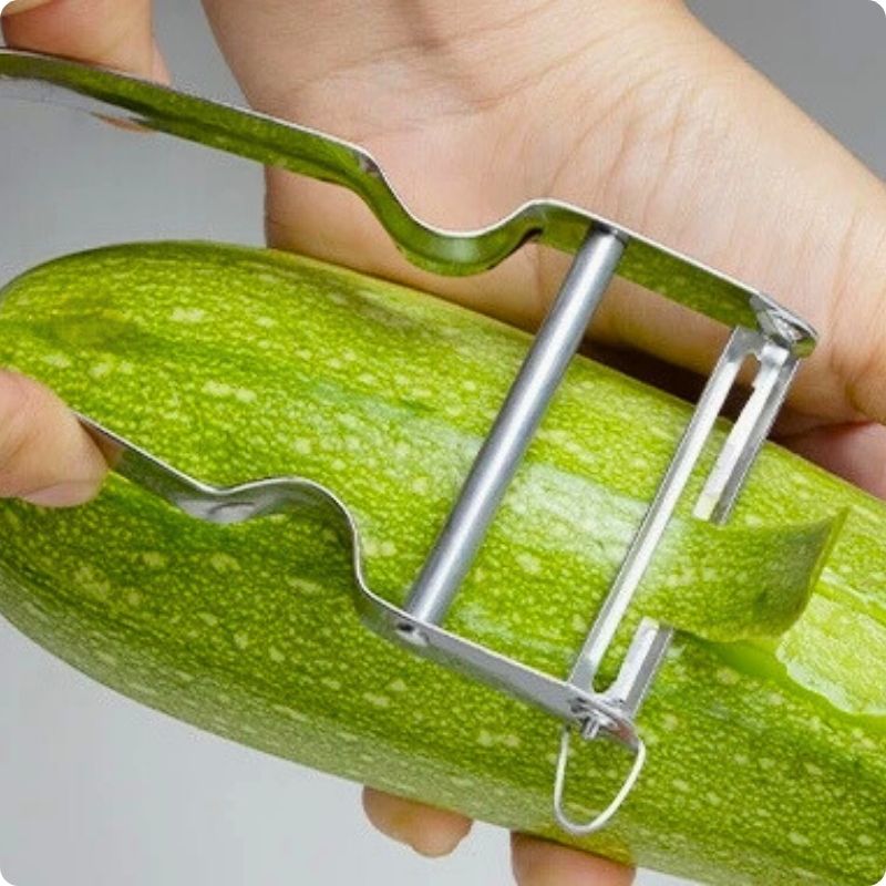 Personne épluchant courgette avec éplucheur à légumes