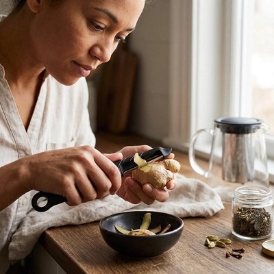 Éplucheur à légumes utilisé par une femme qui épluche du gingembre