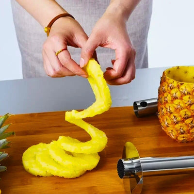 Personne qui tient au-dessus d'une table de l'ananas coupé avec à côté l'éplucheur.