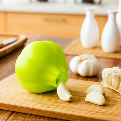 Éplucheur posé sur une planche à découper en bois dans une cuisine, à côté des gousses d'ail épluchées.