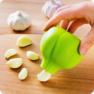 Personne qui tient dans sa main un éplucheur, duquel elle fait sortir une gousse d'ail épluchée et qu'elle pose sur une planche à découper en bois.
