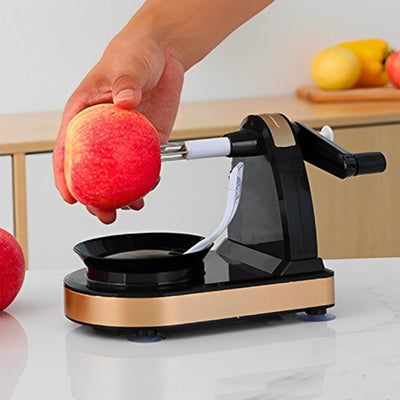 Personne en train de mettre une pomme sur un éplucheur à pomme avec sa main droite, l'éplucheur est posé sur une table avec en fond un plan de travail avec des fruits posés dessus.