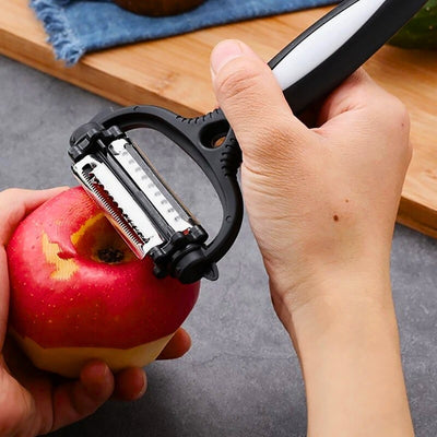 Personne en train d'éplucher une pomme avec un éplucheur noir, il tient la pomme dans sa main gauche et l'éplucheur dans sa main droite, en fond une planche à découper en bois.