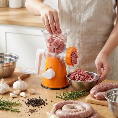 Femme en cuisine qui utilise le hachoir à viande manuel 