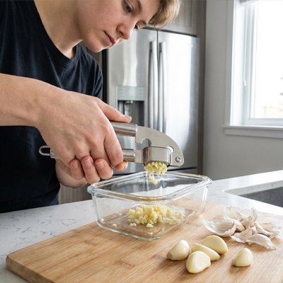 Femme qui utilise l'écraseur ail en cuisine