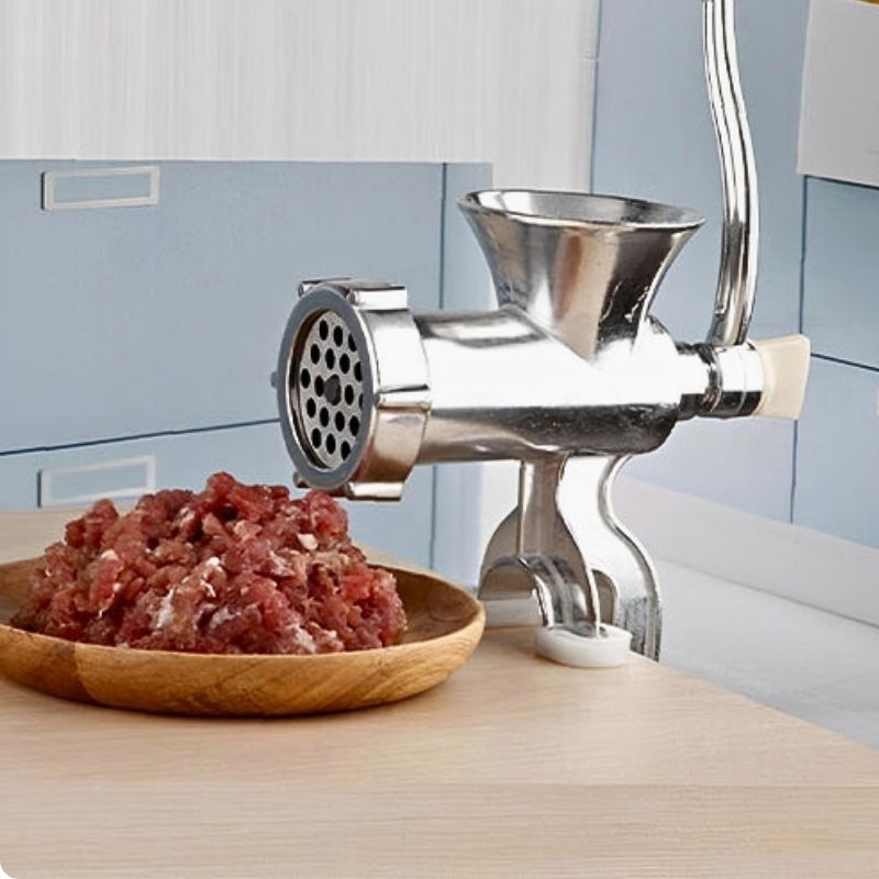 Hachoir à viande carni'ine sur table devant assiette viande hachée