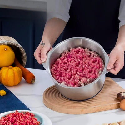 Personne qui tient le réservoir d'un hachoir à viande remplit de viande hachée et posé sur une planche à découper à côté d'une carotte et d'une petite citrouille.