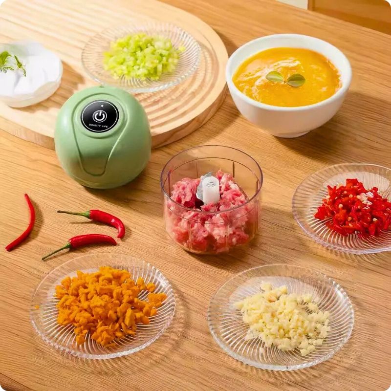 Hachoir électrique vert ouvert avec ramequin de légumes et viande