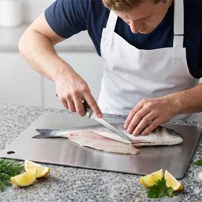 Homme qui découpe du poisson sur la planche a decouper 