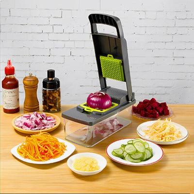 Mandoline cuisine avec réservoir posée sur une table avec des assiettes remplies de légumes coupés de différentes manières.