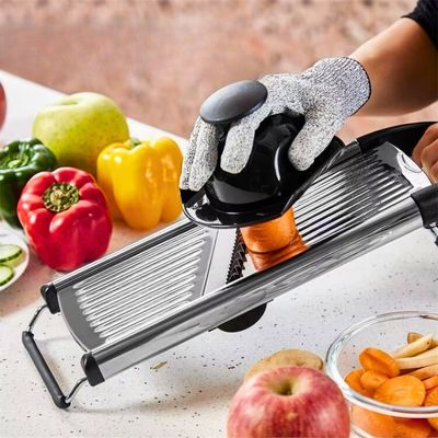 Mandoline japonaise utilisée par une personne avec son protège doigt pour couper une carotte.