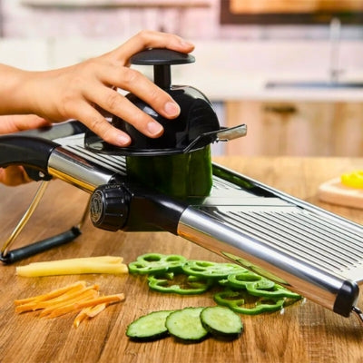 Mandoline japonaise posée sur une table et utilisée par une personne pour couper un légume, on voit sous la mandoline des légumes coupés de différentes façons, la personne utilise un bouchon de protection pour couper le légume.