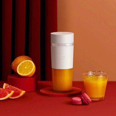 Mixeur pour smoothie posé sur table à côté d'un verre de fruit.