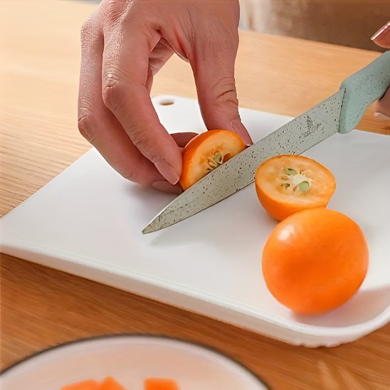 Personne qui coupe un fruit sur la planche à découper