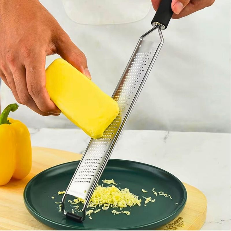 Personne qui utilise un zesteur pour râper du fromage.