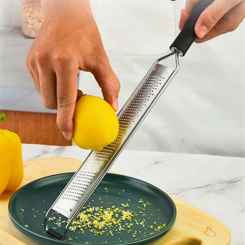 Personne qui utilise un zesteur pour récupérer des zestes de citron.