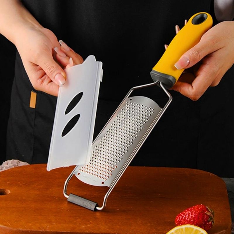 Personne tenant une râpe à fromage et sa protection.